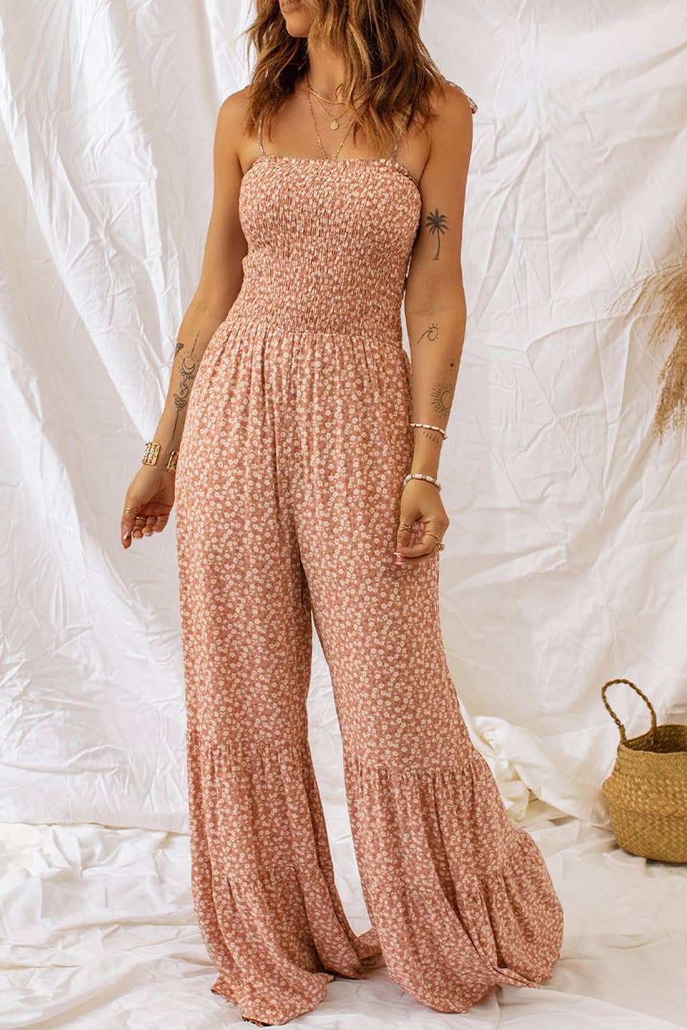 Woman wearing a pink floral jumpsuit against a white background