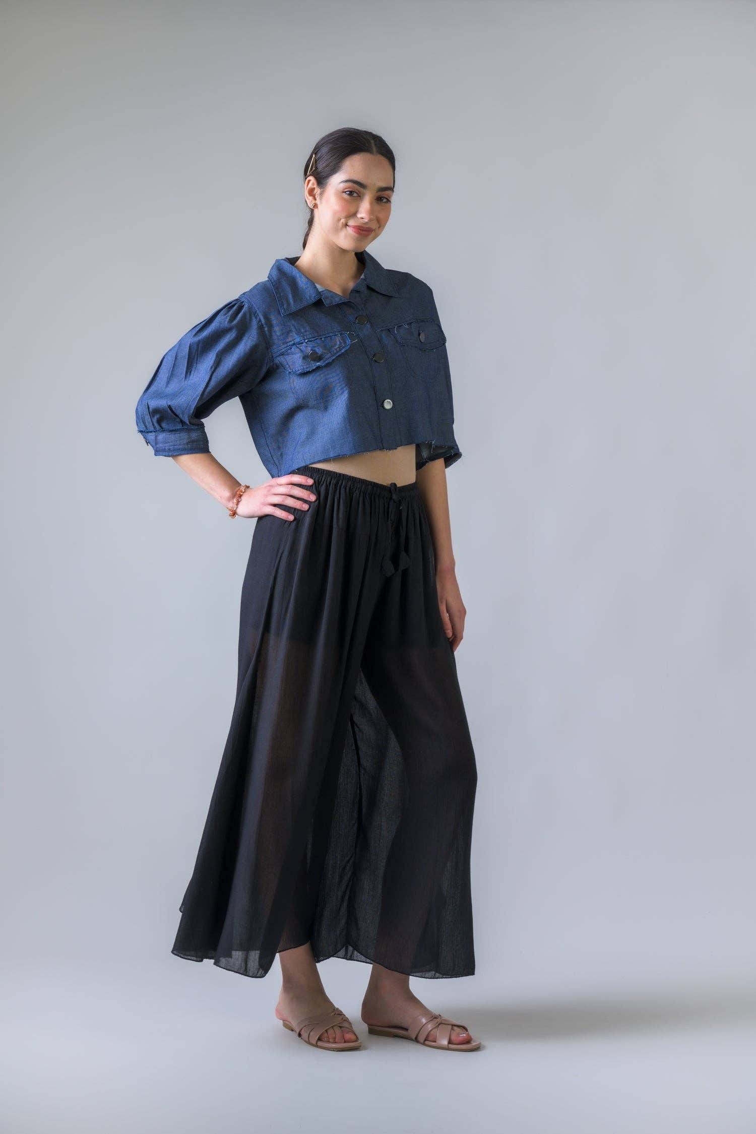 Woman wearing a blue denim shirt and black skirt against a gray background
