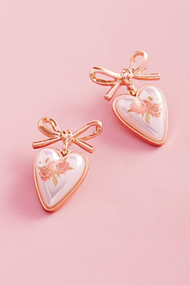 Heart-shaped earrings with floral designs on a pink background
