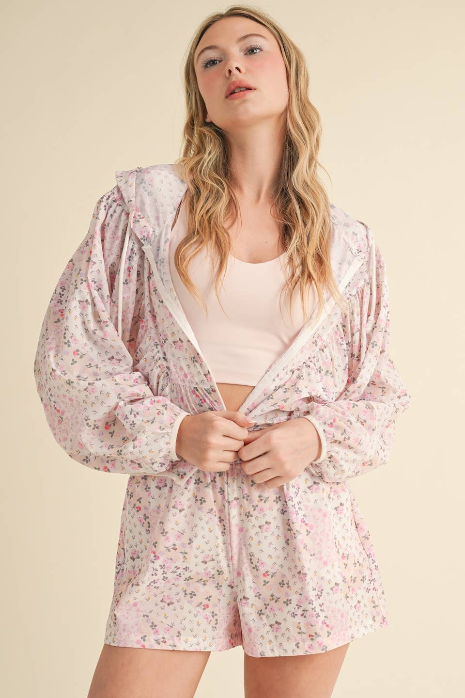Woman wearing a floral pajama set with a matching robe on a beige background
