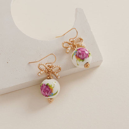 Round-shaped ceramic bead brass hook earrings by Designature New York featuring ceramic beads and brass hooks.