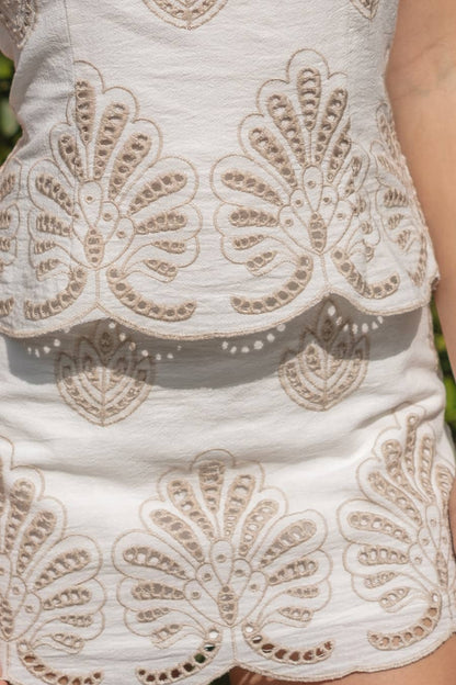 Calla embroidered strapless mini dress by ILLA ILLA featuring intricate embroidery and a fitted strapless design, shown on a model.