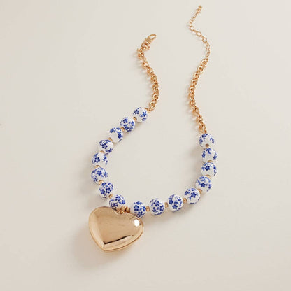 Designature New York puffy heart necklace with ceramic bead, short chain, delicate jewelry accessory with heart charm and beaded detail.