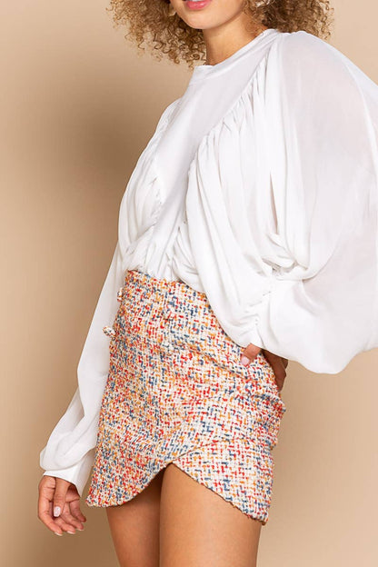 Woman wearing a white blouse and colorful patterned skirt on a beige background